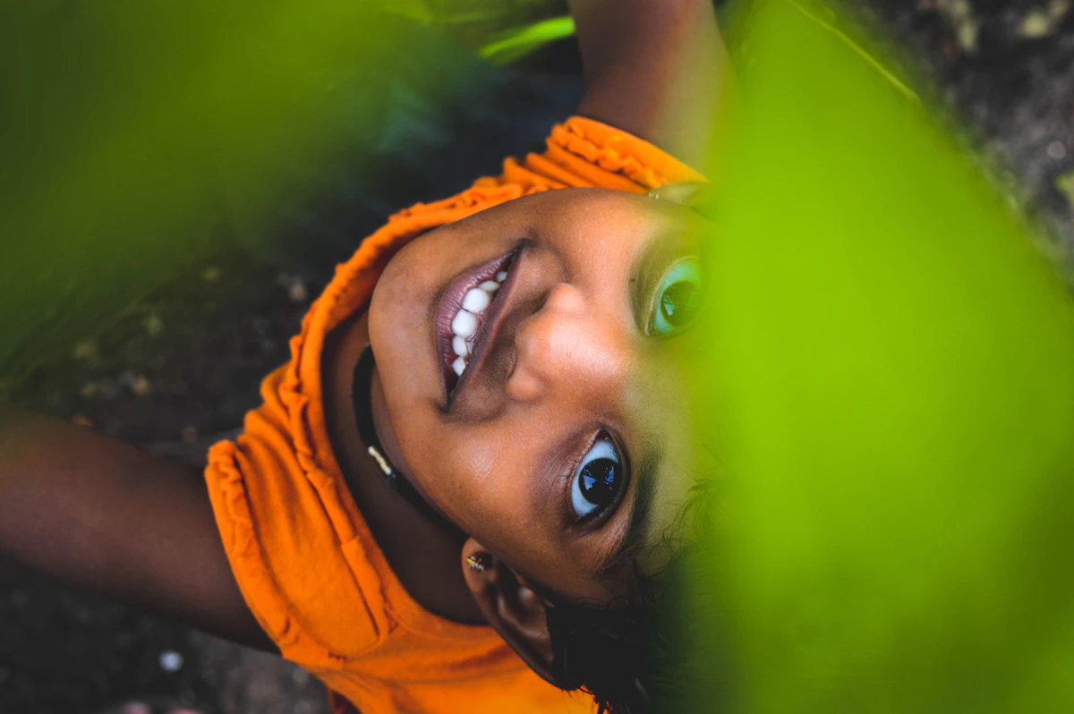 Smiling girl under green leaves