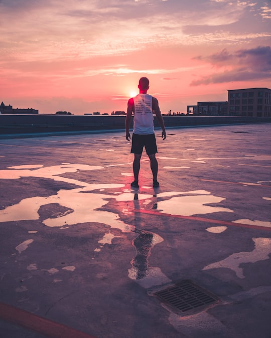 man standing above gray concrete area facing large buildings at golden hour in Lake View United States