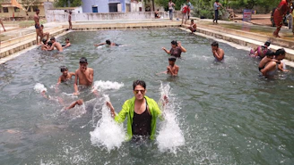 A lively aqua dance party with participants splashing and smiling in a sunlit pool.