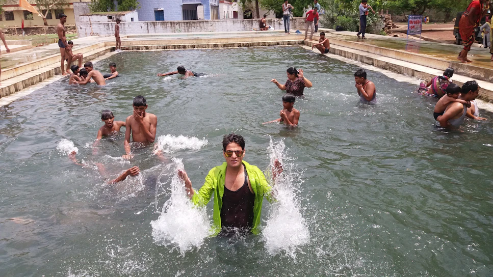 A lively aqua dance party with participants splashing and smiling in a sunlit pool.