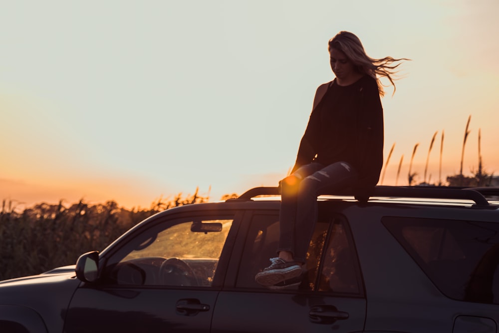 ゴールデンアワーに撮影された車の屋根に座る女性