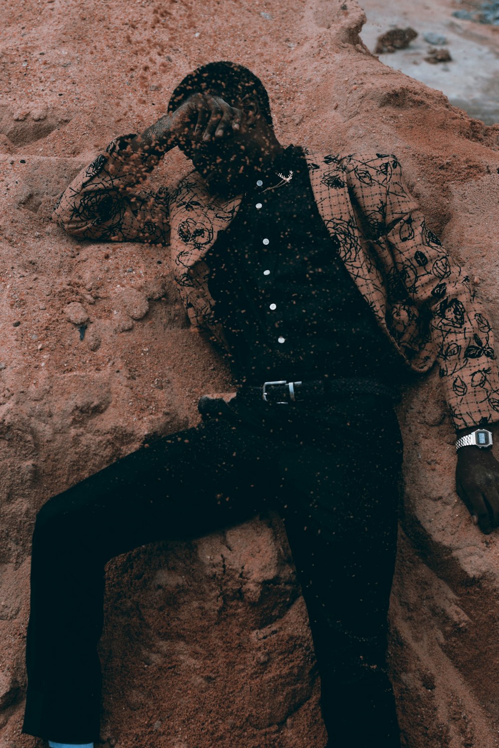 man wearing brown jacket lying on sand