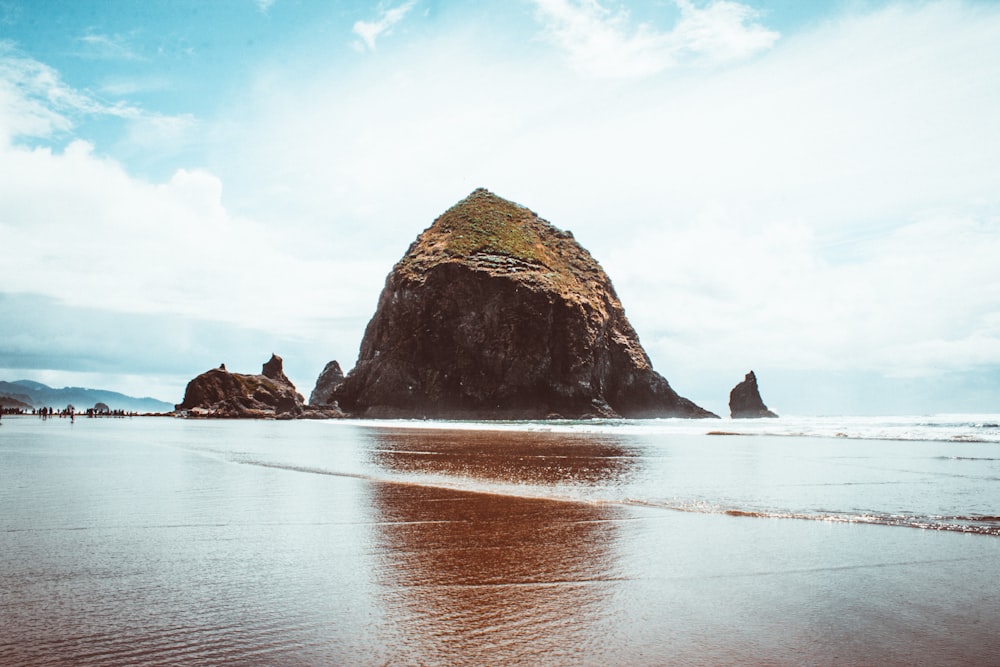 brown rock formation surrounded by water