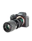 A professional digital camera with a large lens attached, featuring a sleek black body and various adjustment dials. The brand logo is visible on the upper part of the camera.