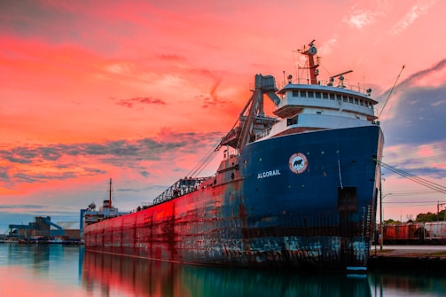 Cargo ship docked at a busy international port during sunset