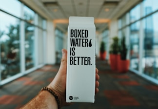 person holding boxed water is better box