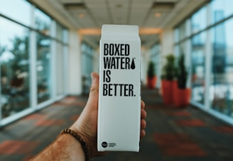 person holding boxed water is better box