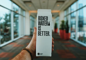 person holding boxed water is better box