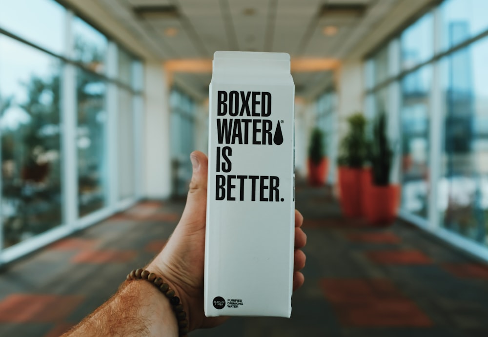 person holding boxed water is better box