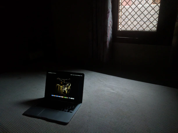 A cozy, dimly lit room with a laptop showing a preview of a provider's profile on Nocturna.