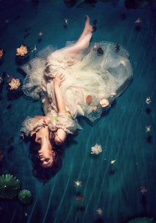 woman wearing dress and lying on teal cloth