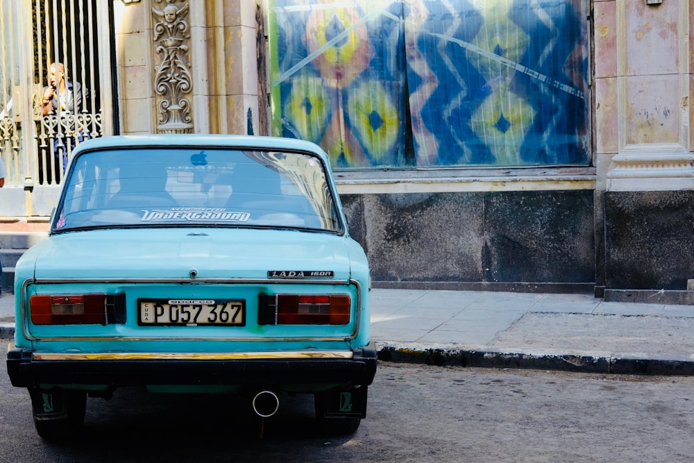 parked teal vehicle near building