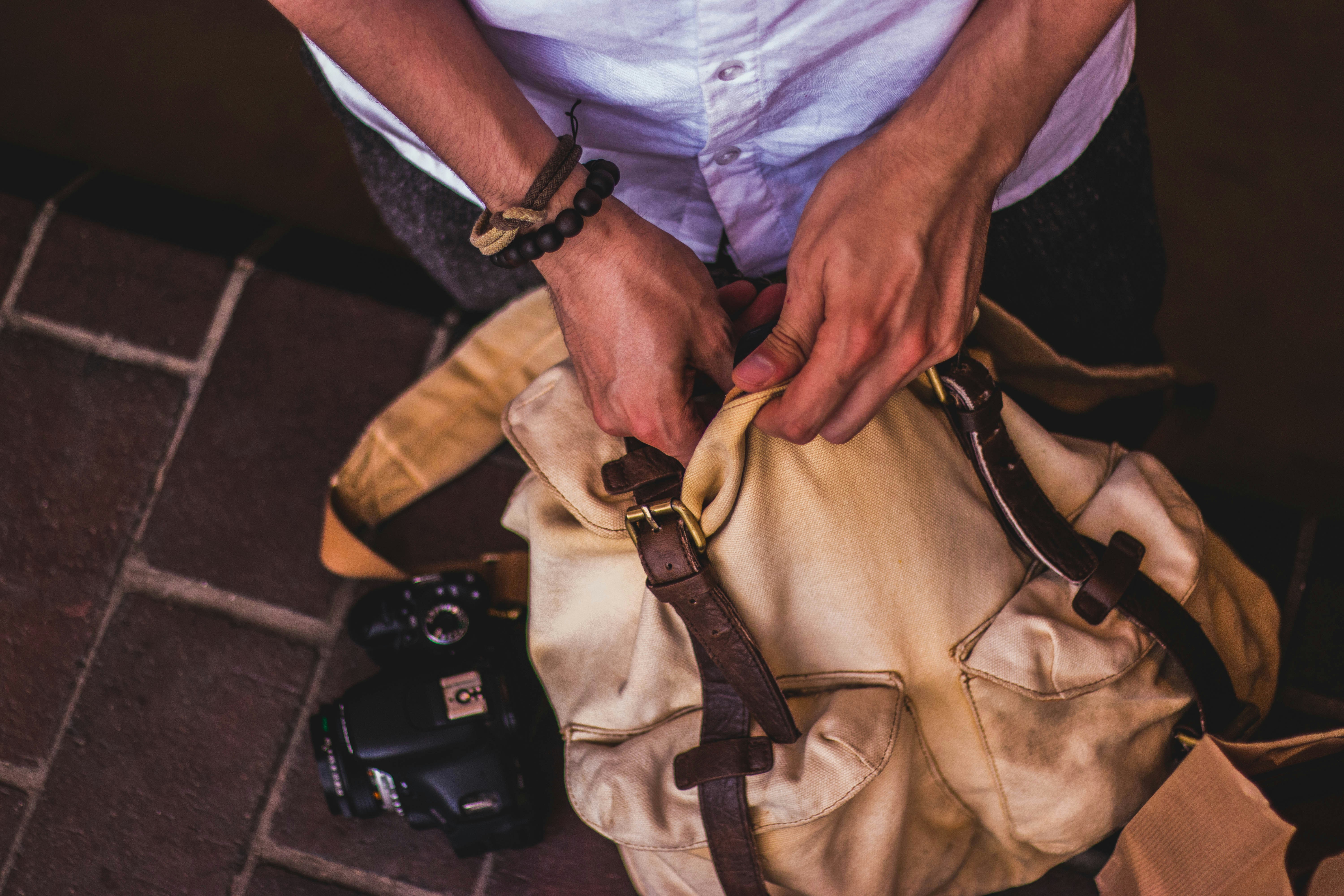 A brown hiking bag being packed by a person largely offscreen.