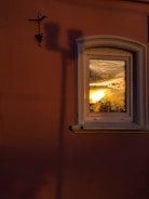 Modern aluminium window panel reflecting a sunset over a cozy living room