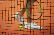 person wearing pair of white low-top sneakers while holding Wilson tennis racket