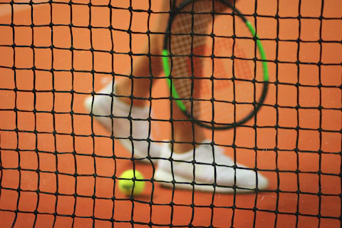 person wearing pair of white low-top sneakers while holding Wilson tennis racket