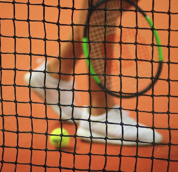 person wearing pair of white low-top sneakers while holding Wilson tennis racket