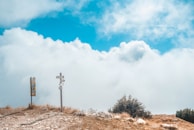 A scenic mountain path marked by trail signs and waypoints under a clear sky.