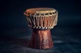 A handcrafted wooden drum with intricate shamanic carvings glowing softly in natural light.