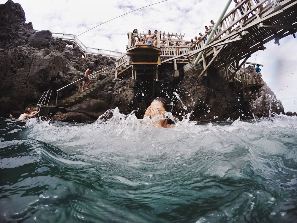 woman swimming in water below bridge