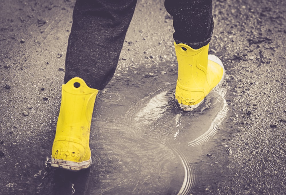 Botas de lluvia amarillas en suelo mojado