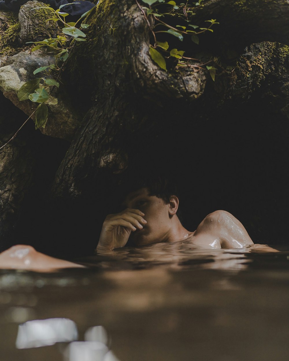a man laying in the water next to a tree