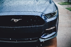 the front of a blue mustang parked on the side of the road