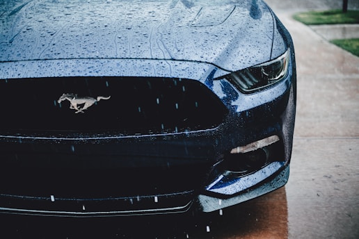 the front of a blue mustang parked on the side of the road