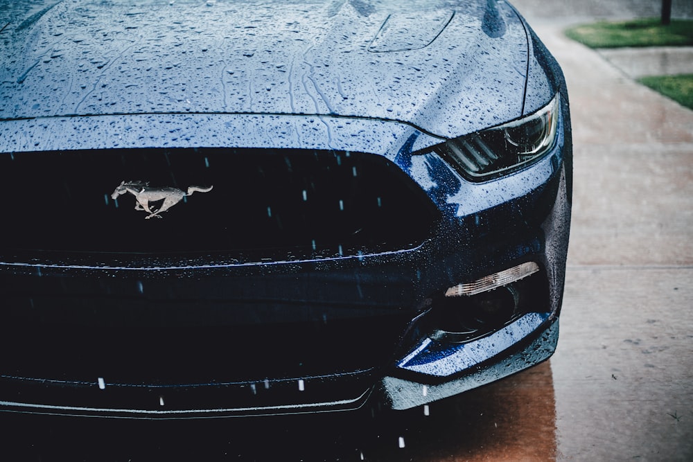 the front of a blue mustang parked on the side of the road