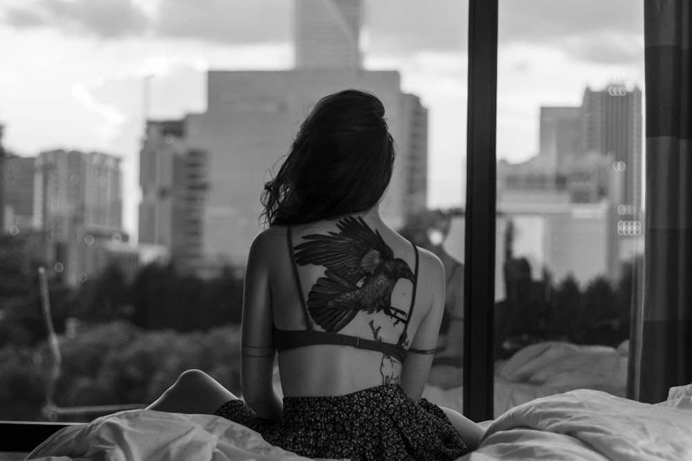 Graustufenfotografie einer Frau, die auf einer Bettdecke sitzt