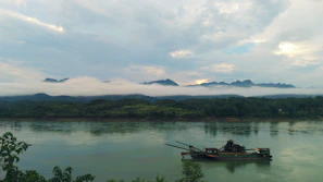A peaceful morning scene of a solo traveler standing on the bow of a river cruise ship, taking in the misty European countryside.