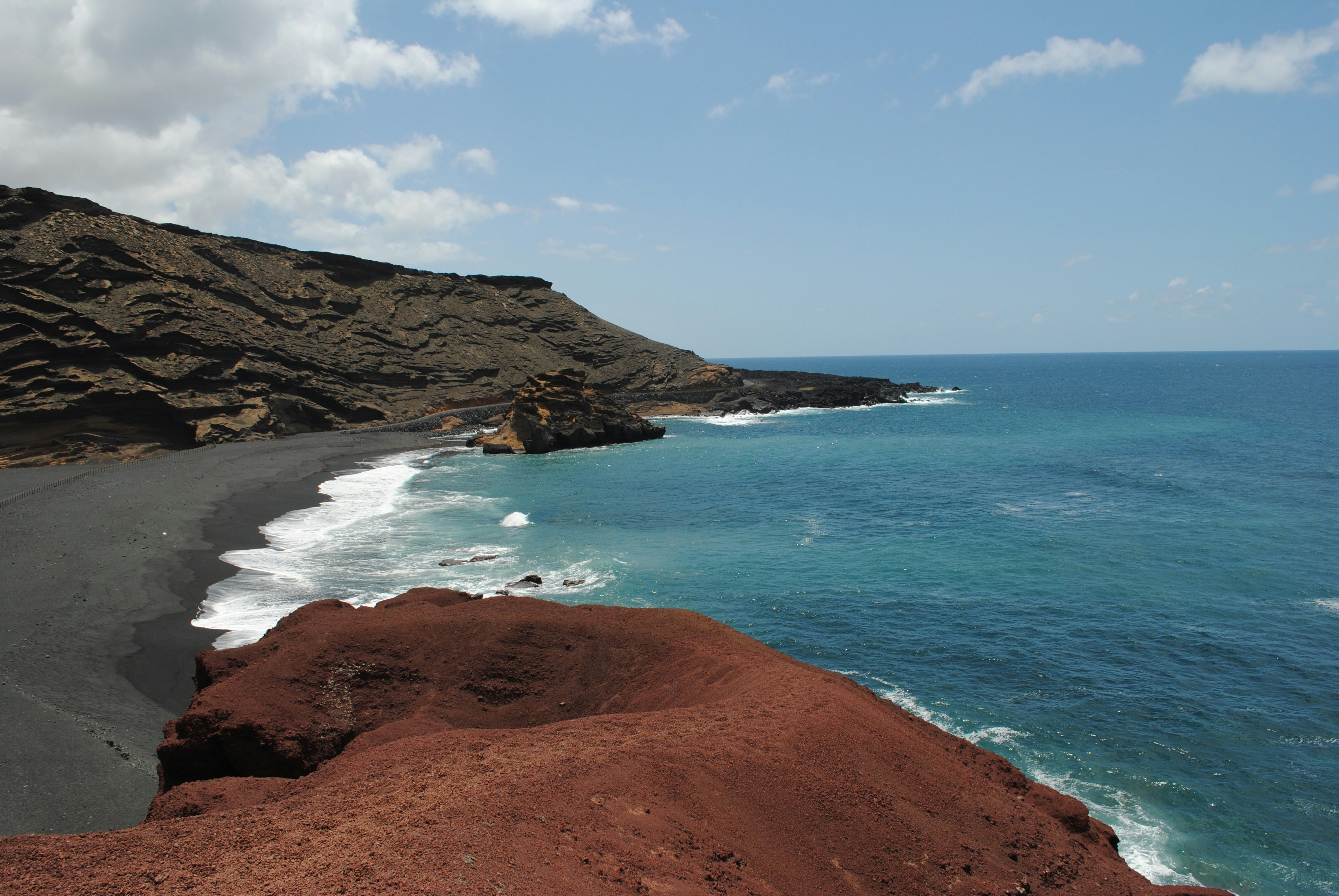 Volcanic red beach in Santorini with dramatic red and black cliffs meeting crystal clear water