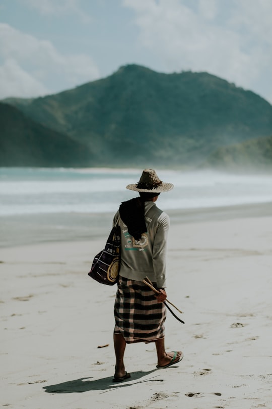 man walking on shore under sunny sky in Lombok Indonesia