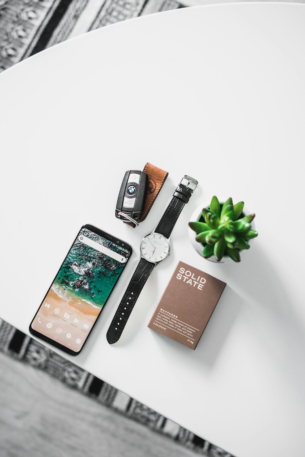 Flat-Lay-Fotografie von Uhr, Smartphone, Autoanhänger und Box