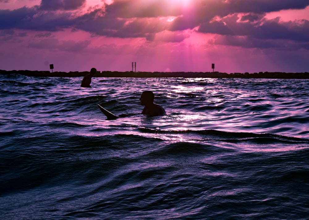 夕暮れ時に海でサーフィンをする人のシルエット