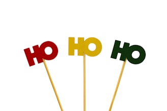 Three wooden sticks topped with the letters 'HO' in different colors are arranged in a line. The letters are made of paper or cardboard.