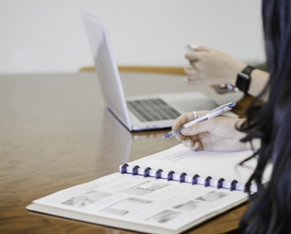 person holding pen writing on paper