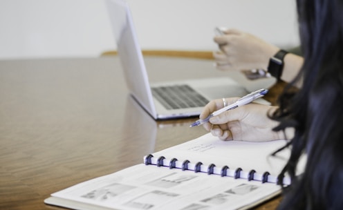 person holding pen writing on paper