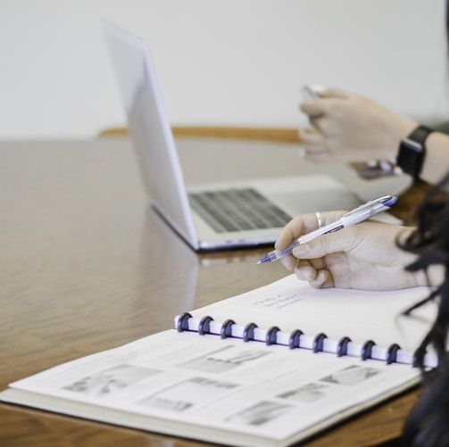 person holding pen writing on paper