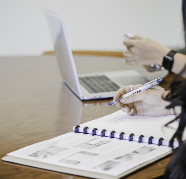 person holding pen writing on paper