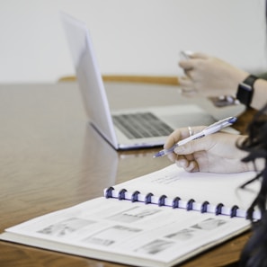 person holding pen writing on paper