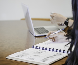 person holding pen writing on paper