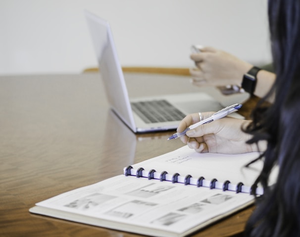 person holding pen writing on paper