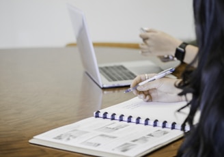 person holding pen writing on paper