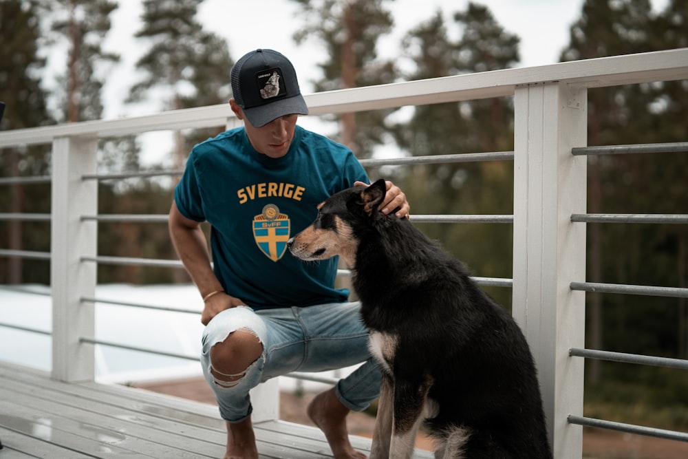 man petting short-coated black and brown dog