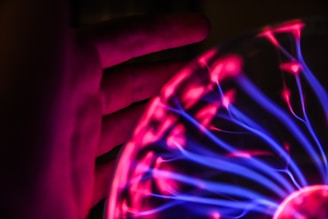 person's hand beside plasma ball