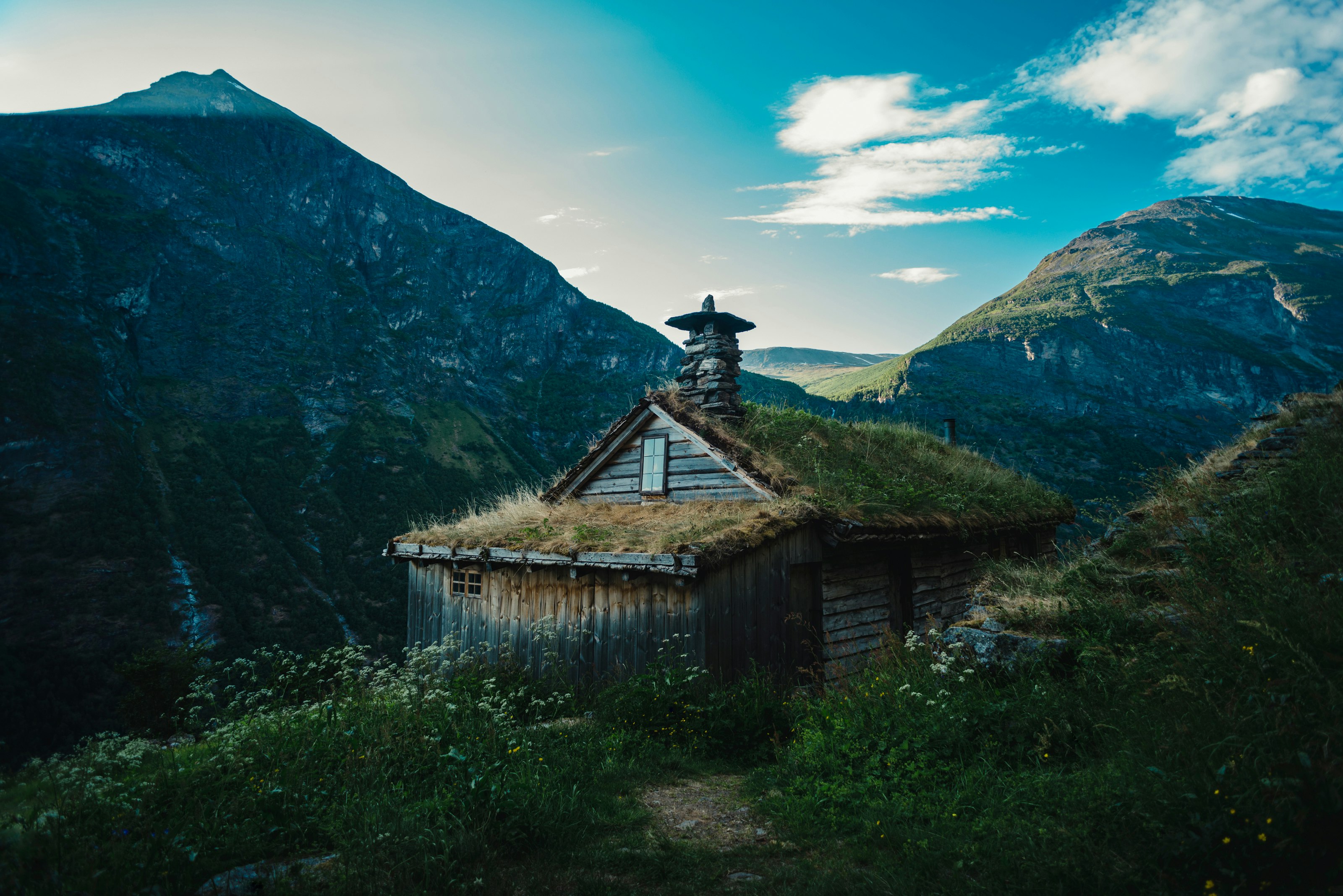 gray wooden house on green mountain