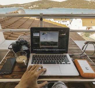 person holding MacBook Pro besides orange power bank