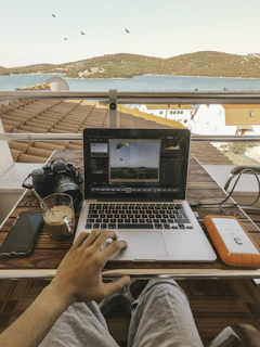 Happy young professional working remotely on a laptop with the Australian coastline visible behind