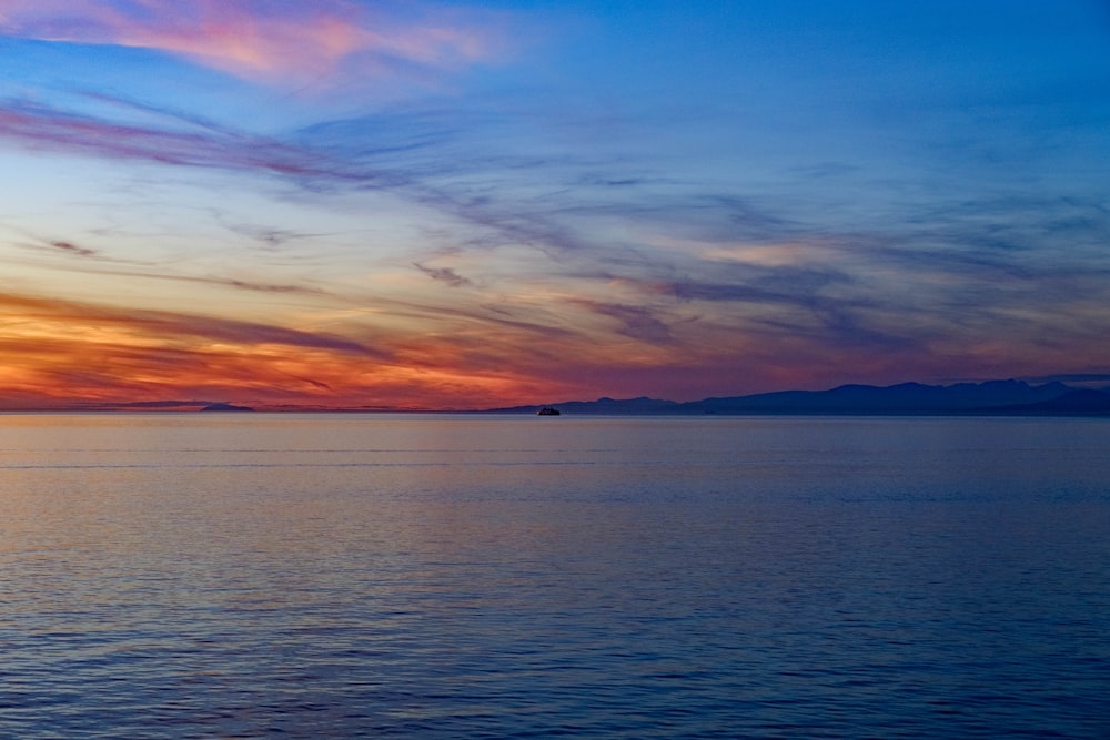 body of water under blue and orange sky